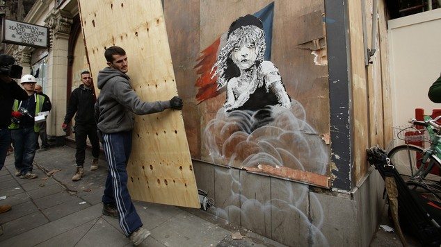 Workmen begin to cover up a new artwork by Banksy opposite the French embassy in Knightsbridge, London
