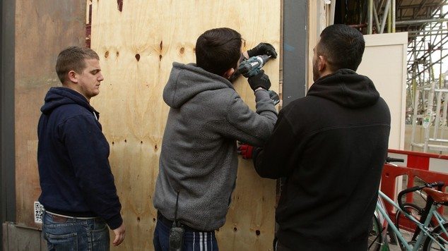 Workmen secure boarding over the latest Banksy in London